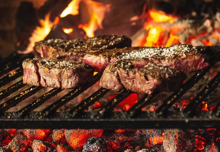 Carnes asándose sobre las brasas en la parrilla de L'equip